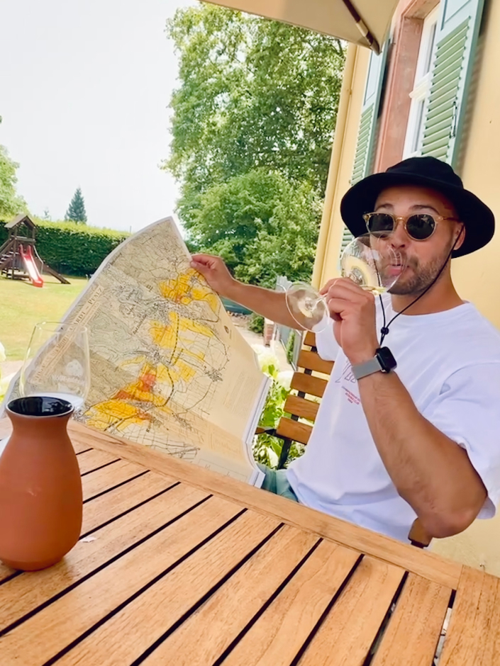 A photo of me drinking a glass of wine while reading a map of the wine region and posing for the camera.